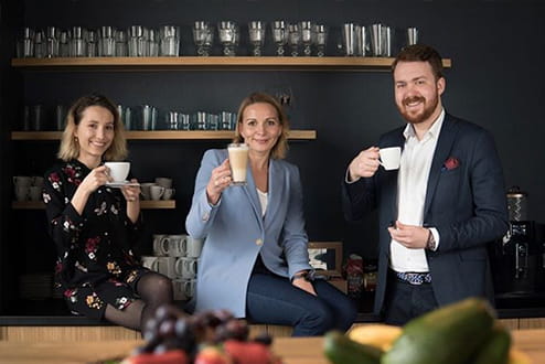 Pracownicy Colliers International pijący kawę w przestrzeni open space w biurze Colliers.